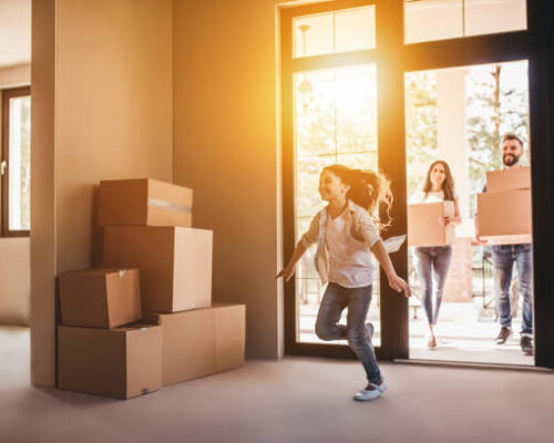 Happy family with cardboard boxes in new house at moving day.